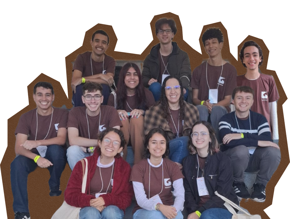 A foto sem fundo mostra os doze membros presentes no evento. Todos estão sentados em uma escada. Apesar de não haver fundo, há uma borda marrom em torno de todos.